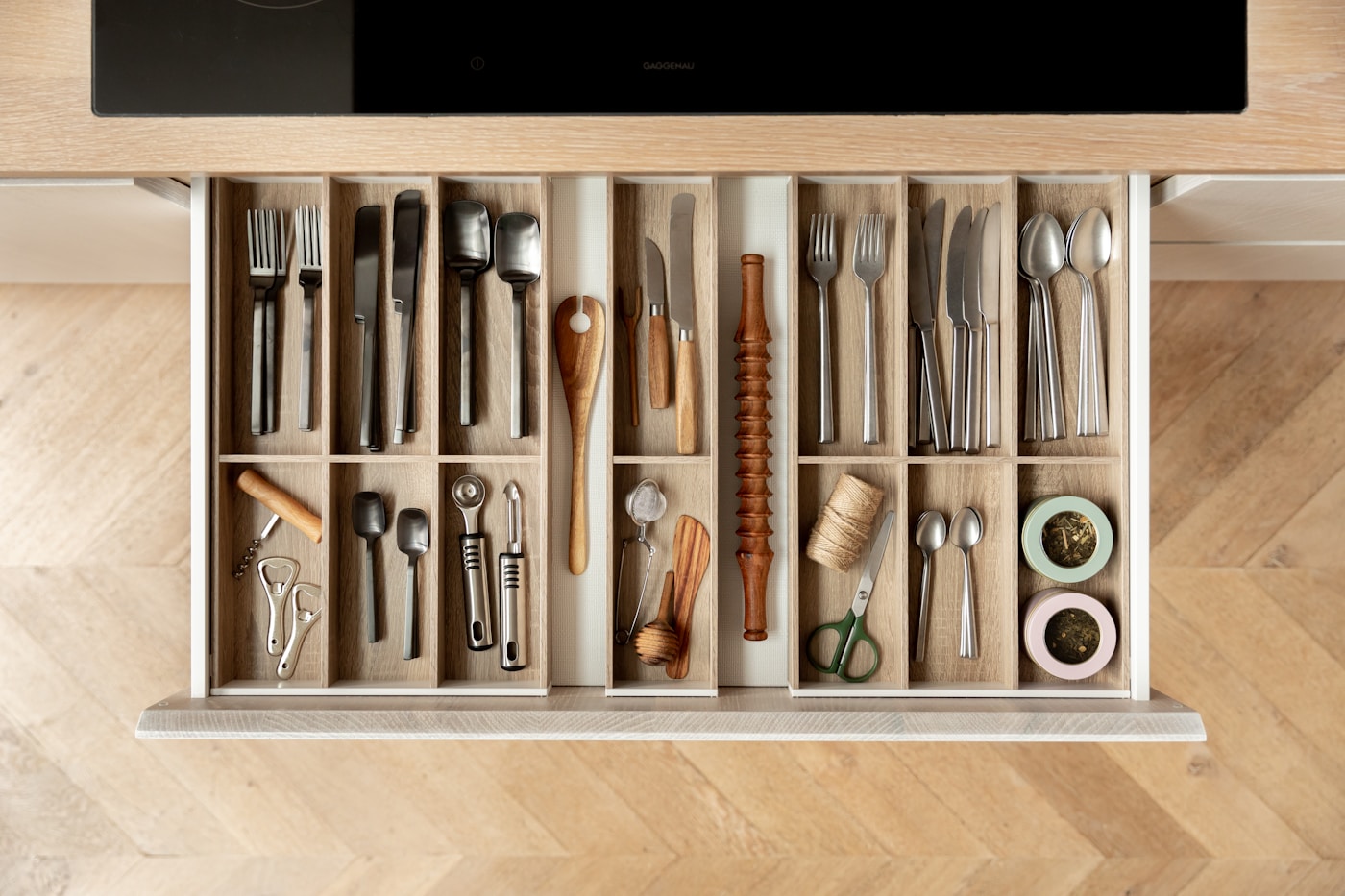 Top view of a kitchen drawer with utensils arranged in wooden inserts.